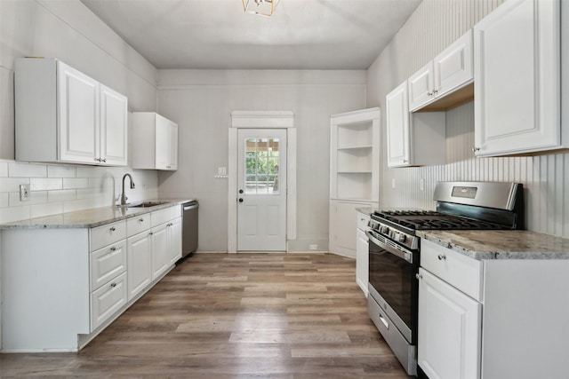 kitchen featuring appliances with stainless steel finishes, white cabinetry, sink, light stone counters, and light wood-type flooring