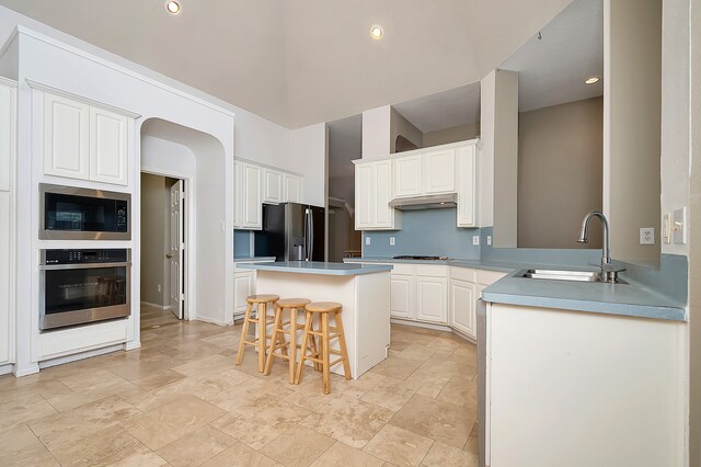 kitchen with a breakfast bar, white cabinets, sink, a kitchen island, and stainless steel appliances