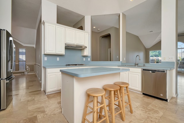 kitchen with kitchen peninsula, a kitchen bar, stainless steel appliances, sink, and white cabinets