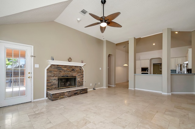 unfurnished living room featuring a fireplace, a textured ceiling, high vaulted ceiling, and ceiling fan