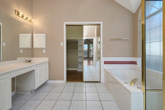 bathroom featuring vanity, lofted ceiling, tile patterned floors, a bathing tub, and plenty of natural light