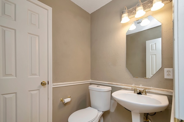 bathroom featuring a textured ceiling, toilet, and sink