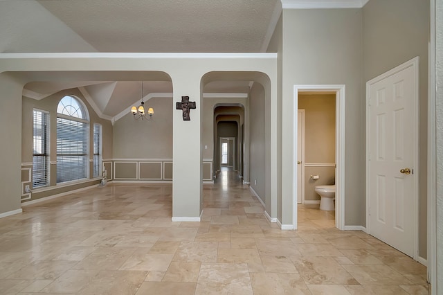 spare room featuring lofted ceiling, crown molding, and an inviting chandelier