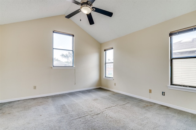 carpeted empty room with ceiling fan, a textured ceiling, vaulted ceiling, and a wealth of natural light