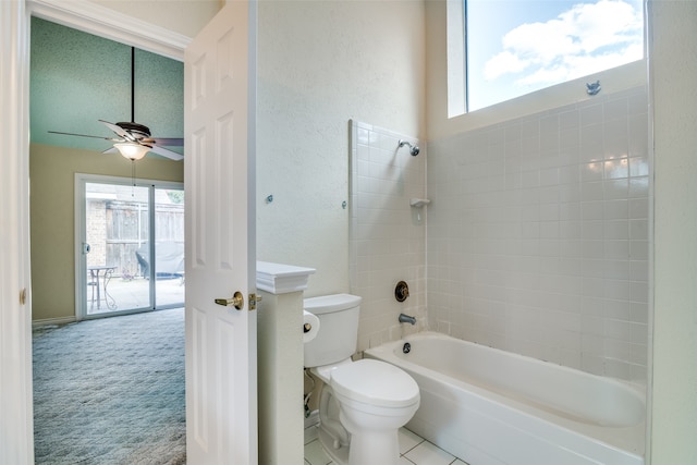 bathroom featuring a wealth of natural light, a textured ceiling, tiled shower / bath combo, and toilet