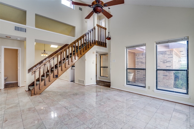 unfurnished living room featuring ceiling fan with notable chandelier and high vaulted ceiling