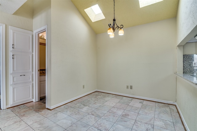 empty room with high vaulted ceiling, a skylight, and an inviting chandelier