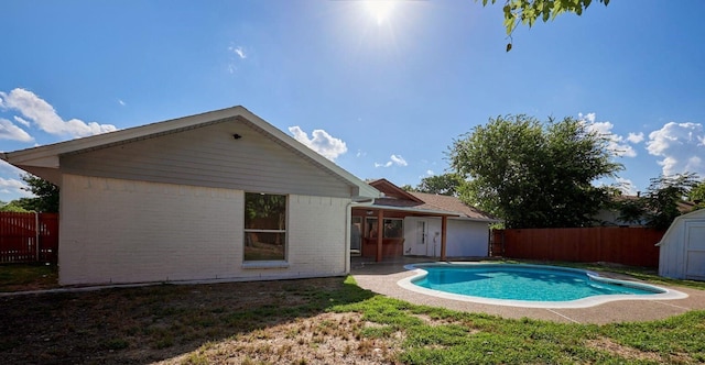 back of property with a fenced in pool and a storage unit