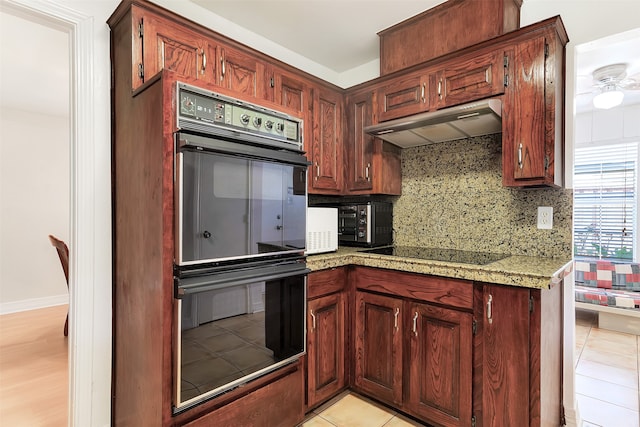 kitchen with light hardwood / wood-style floors, black appliances, decorative backsplash, and light stone counters