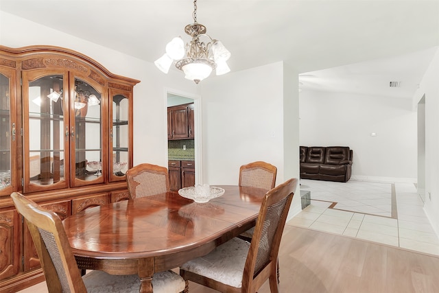 dining room with light wood-type flooring and a notable chandelier