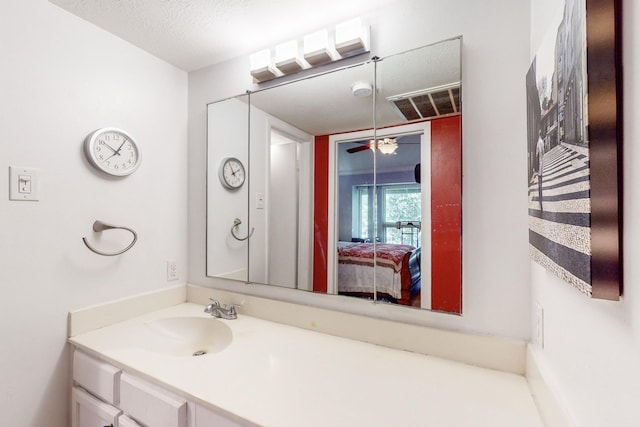 bathroom with ceiling fan, vanity, and a textured ceiling