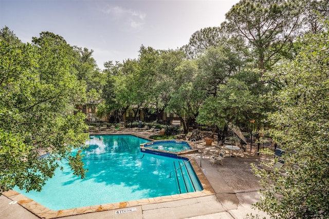 view of swimming pool featuring a patio and a hot tub