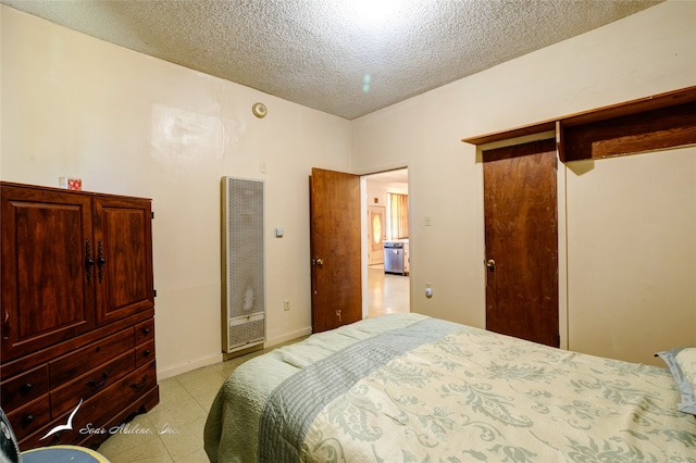 bedroom with a closet, light tile patterned floors, and a textured ceiling