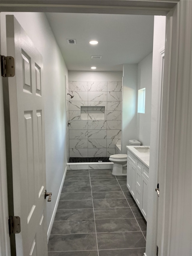 bathroom with vanity, tiled shower, toilet, and tile patterned floors