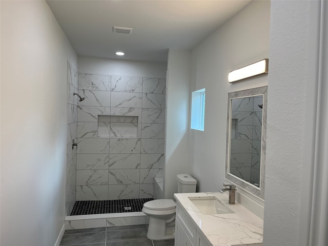 bathroom featuring vanity, tiled shower, toilet, and tile patterned flooring