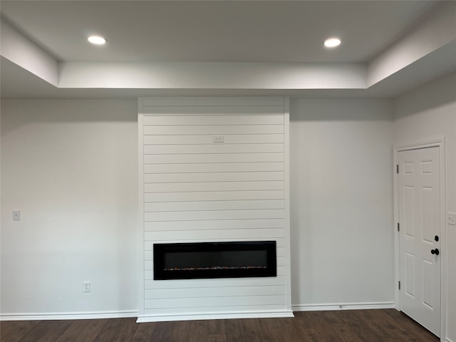 unfurnished living room with a fireplace, a raised ceiling, and dark hardwood / wood-style flooring