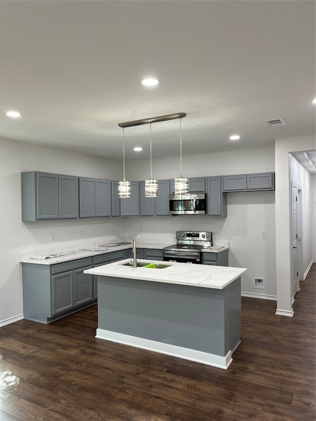 kitchen featuring appliances with stainless steel finishes, a kitchen island with sink, sink, and dark wood-type flooring