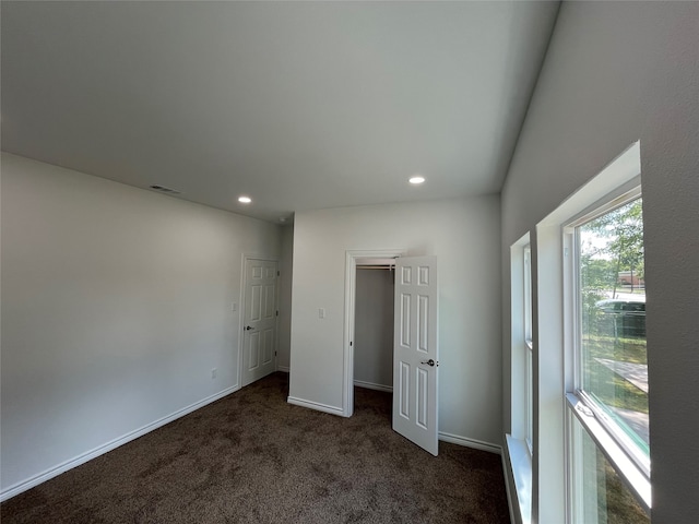 unfurnished bedroom featuring dark carpet and a closet