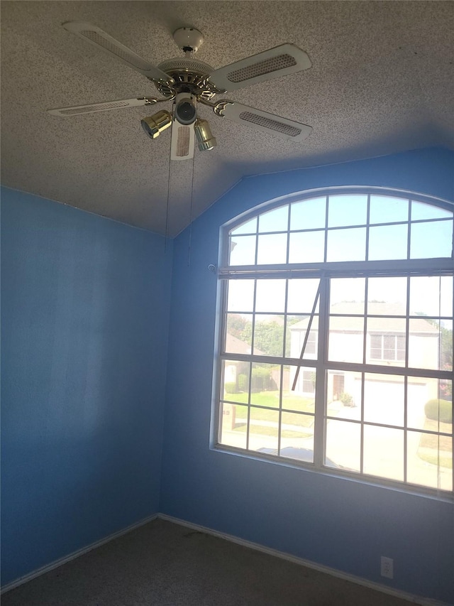 empty room featuring lofted ceiling, ceiling fan, and a textured ceiling