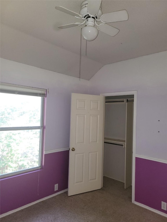 unfurnished bedroom with ceiling fan, a closet, carpet, and lofted ceiling