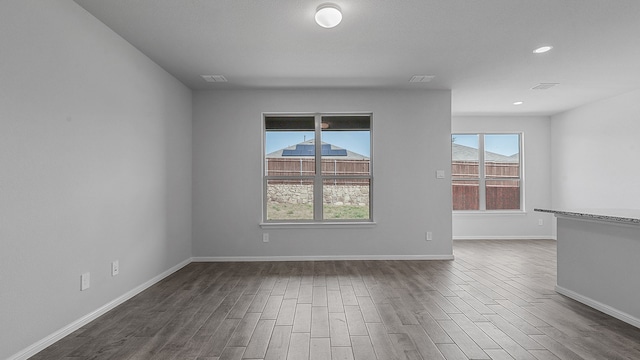 spare room with a wealth of natural light and wood-type flooring