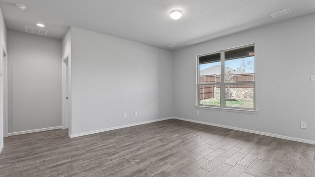 unfurnished room with a textured ceiling and light wood-type flooring