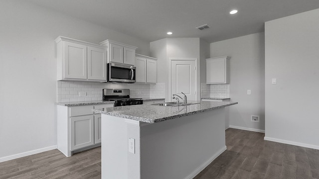 kitchen with white cabinets, stainless steel appliances, an island with sink, and sink