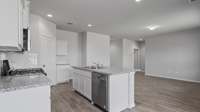 kitchen with white cabinets, backsplash, light hardwood / wood-style flooring, appliances with stainless steel finishes, and a kitchen island with sink