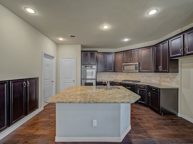 kitchen featuring dark brown cabinets, dark wood-type flooring, stainless steel appliances, decorative backsplash, and sink