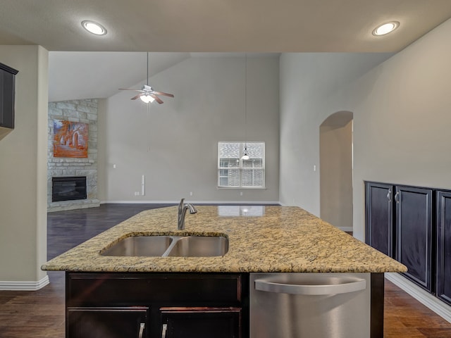 kitchen featuring stainless steel dishwasher, a fireplace, light stone countertops, and dark hardwood / wood-style floors