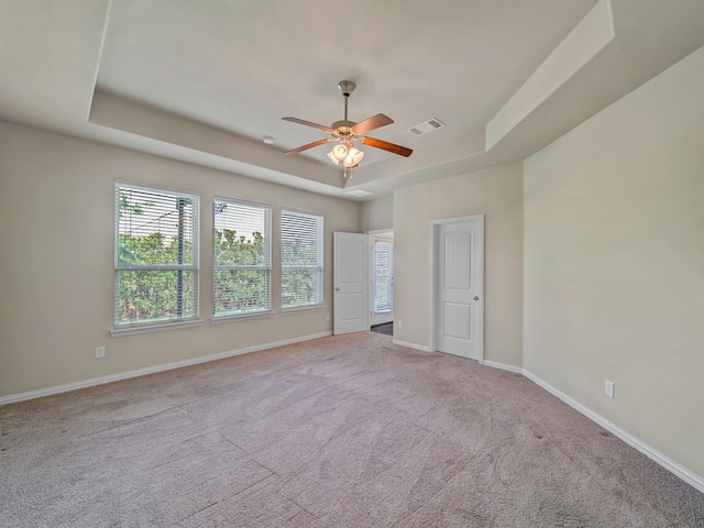 spare room with ceiling fan, carpet, and a tray ceiling