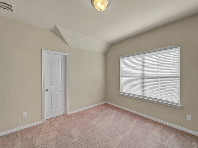 carpeted empty room featuring lofted ceiling