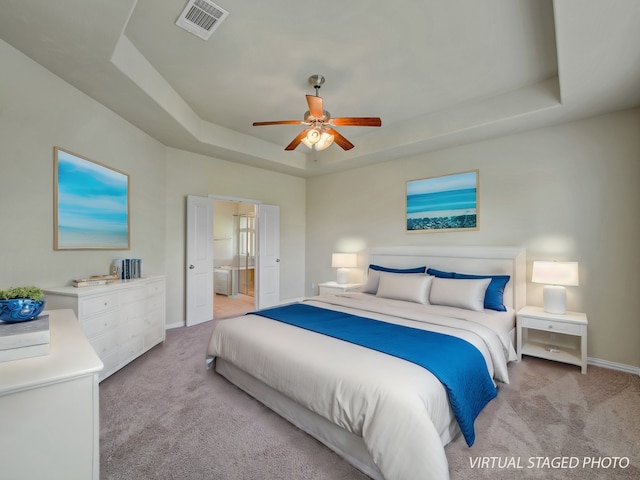 bedroom featuring carpet floors, ensuite bathroom, ceiling fan, and a tray ceiling