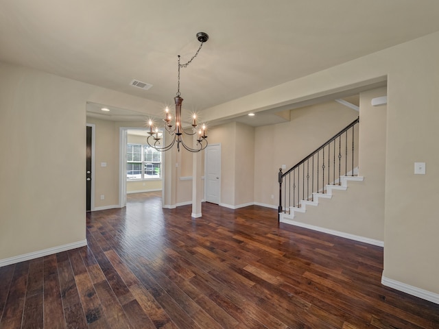 empty room with dark hardwood / wood-style floors and a chandelier