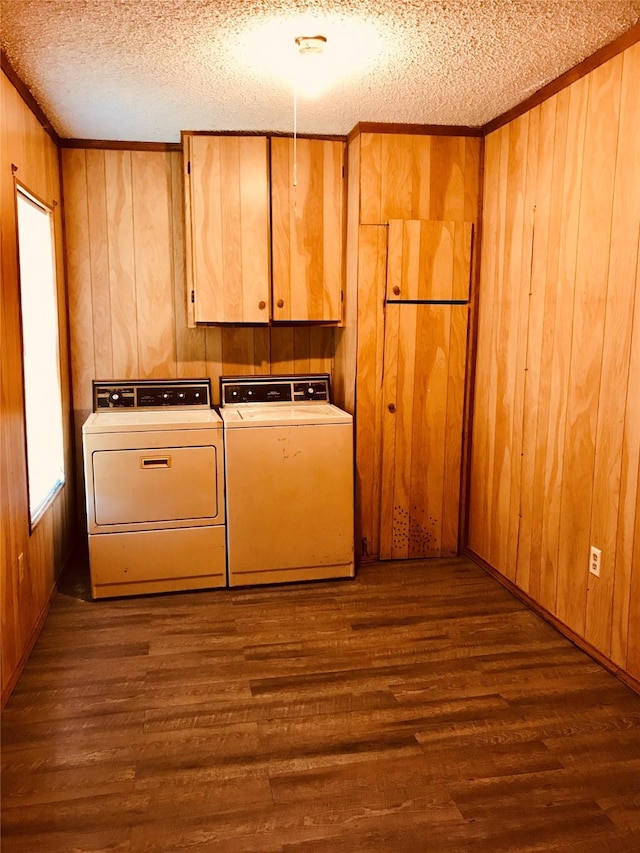 laundry room with a textured ceiling, wooden walls, washer and dryer, dark hardwood / wood-style floors, and cabinets