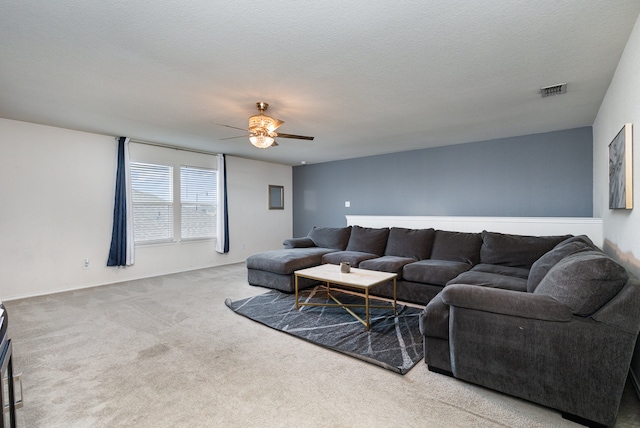 living room featuring ceiling fan, carpet floors, and a textured ceiling