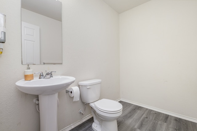 bathroom featuring wood-type flooring, toilet, and sink