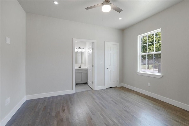 unfurnished bedroom featuring connected bathroom, sink, ceiling fan, light hardwood / wood-style floors, and a closet