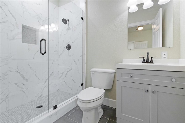 bathroom featuring tile patterned flooring, vanity, a shower with door, and toilet