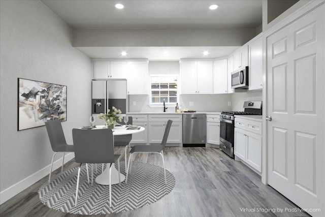 kitchen with white cabinetry, appliances with stainless steel finishes, sink, and light hardwood / wood-style flooring