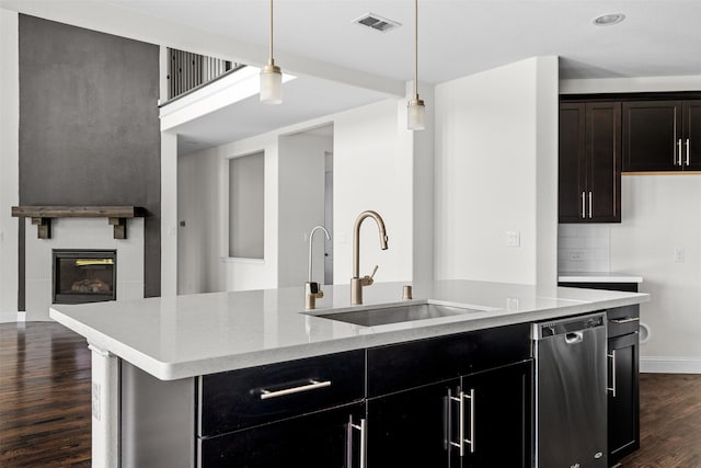 kitchen featuring sink, hanging light fixtures, a kitchen island with sink, stainless steel dishwasher, and decorative backsplash