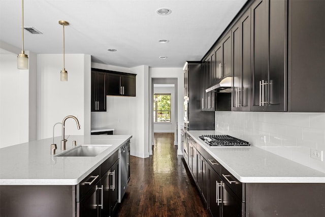 kitchen with sink, stainless steel appliances, light stone counters, pendant lighting, and decorative backsplash