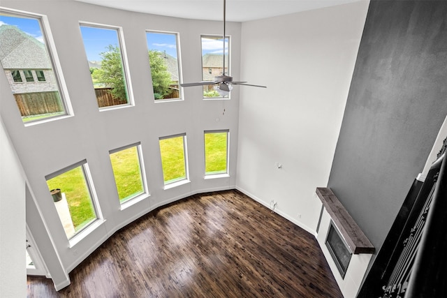 unfurnished living room with plenty of natural light, dark wood-type flooring, and ceiling fan