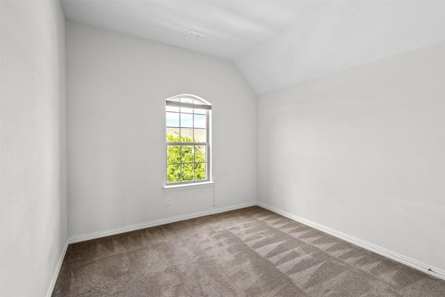 spare room featuring carpet and vaulted ceiling