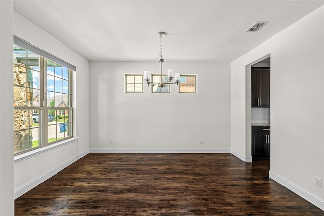 unfurnished dining area featuring dark hardwood / wood-style flooring and an inviting chandelier