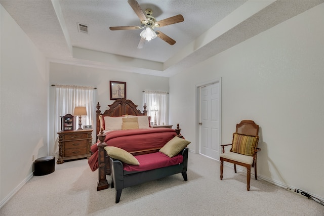 bedroom with carpet floors, a textured ceiling, ceiling fan, and a tray ceiling