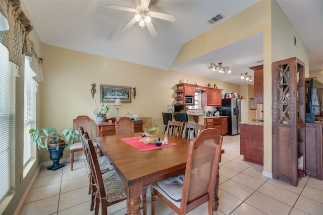 tiled dining space featuring a textured ceiling, rail lighting, vaulted ceiling, and ceiling fan