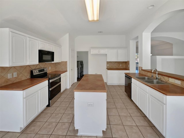 kitchen featuring black appliances, decorative backsplash, white cabinetry, washing machine and clothes dryer, and sink