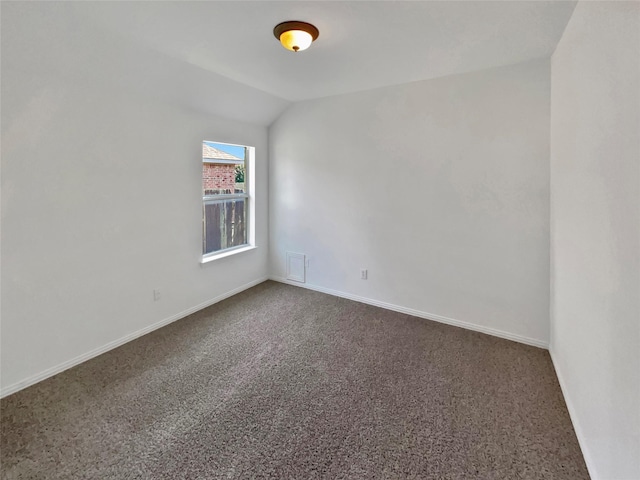 carpeted spare room featuring vaulted ceiling