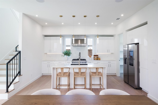 kitchen with light hardwood / wood-style flooring, white cabinets, stainless steel fridge, and tasteful backsplash